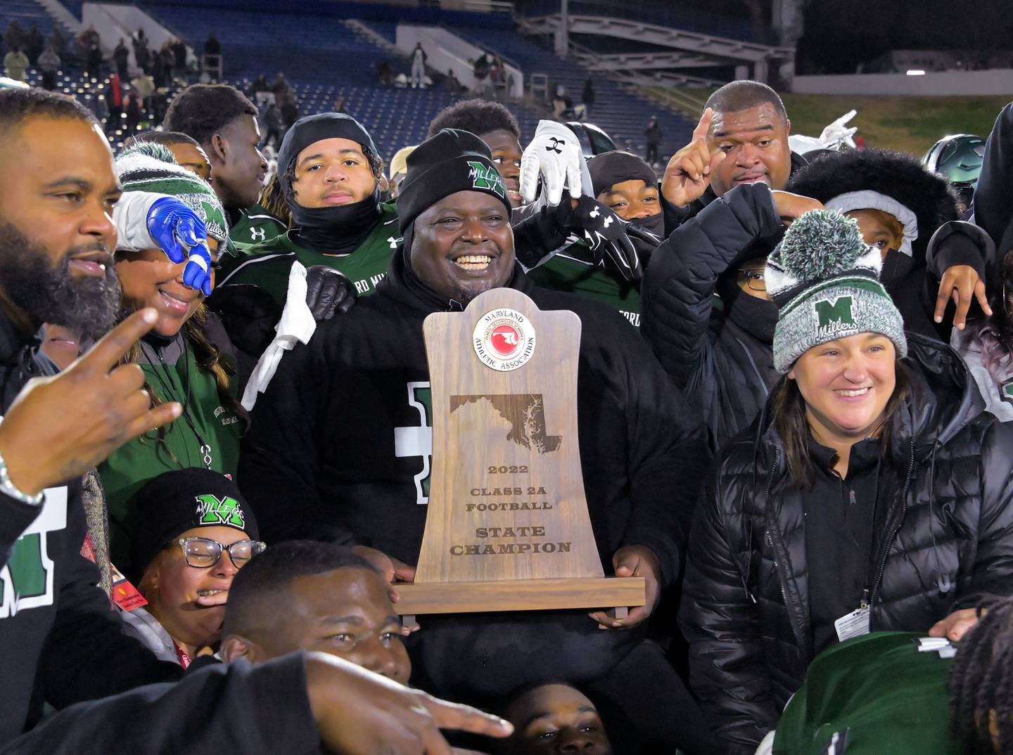 El entrenador de fútbol de Milford Mill, Reggie White, sostiene el trofeo después de derrotar a Kent Island en el juego de campeonato estatal Clase 2A el viernes por la noche en el Navy-Marine Corps Memorial Stadium.