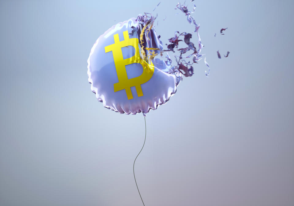 Imagen generada digitalmente de un globo de helio circular púrpura con un signo de bitcoin explotando contra un fondo gris que visualiza el desplome del mercado de valores.