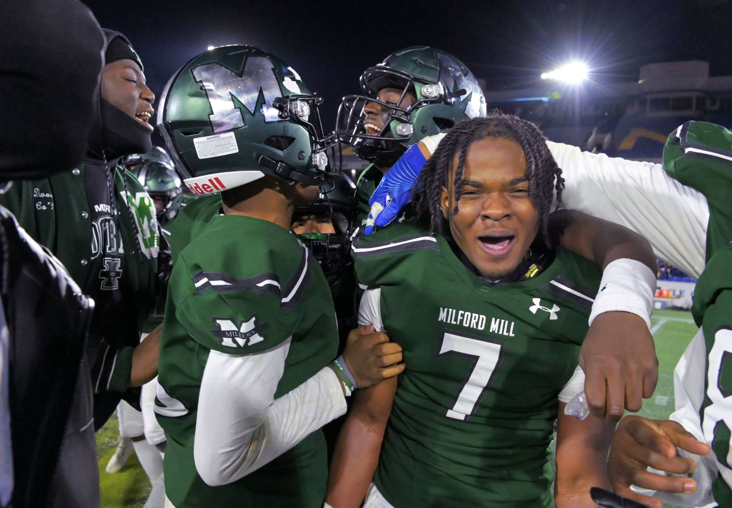 El mariscal de campo de Milford Mill, Deshawn Purdie, en el medio, celebra con sus compañeros de equipo, incluido el liniero defensivo Dre'Yan Pitts, a la izquierda, y el profundo profundo/esquinero Darrell Jackson III, a la derecha, después de derrotar a Kent Island para ganar el campeonato estatal Clase 2A el viernes por la noche en Navy-Marine Estadio Memorial del Cuerpo.