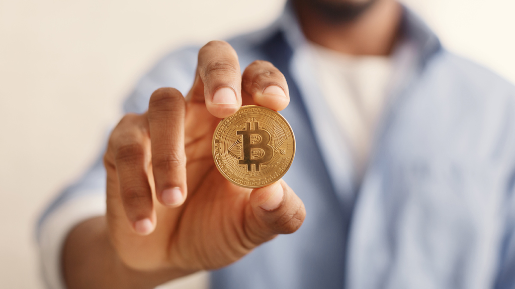 Un hombre sostiene Bitcoin en la mano