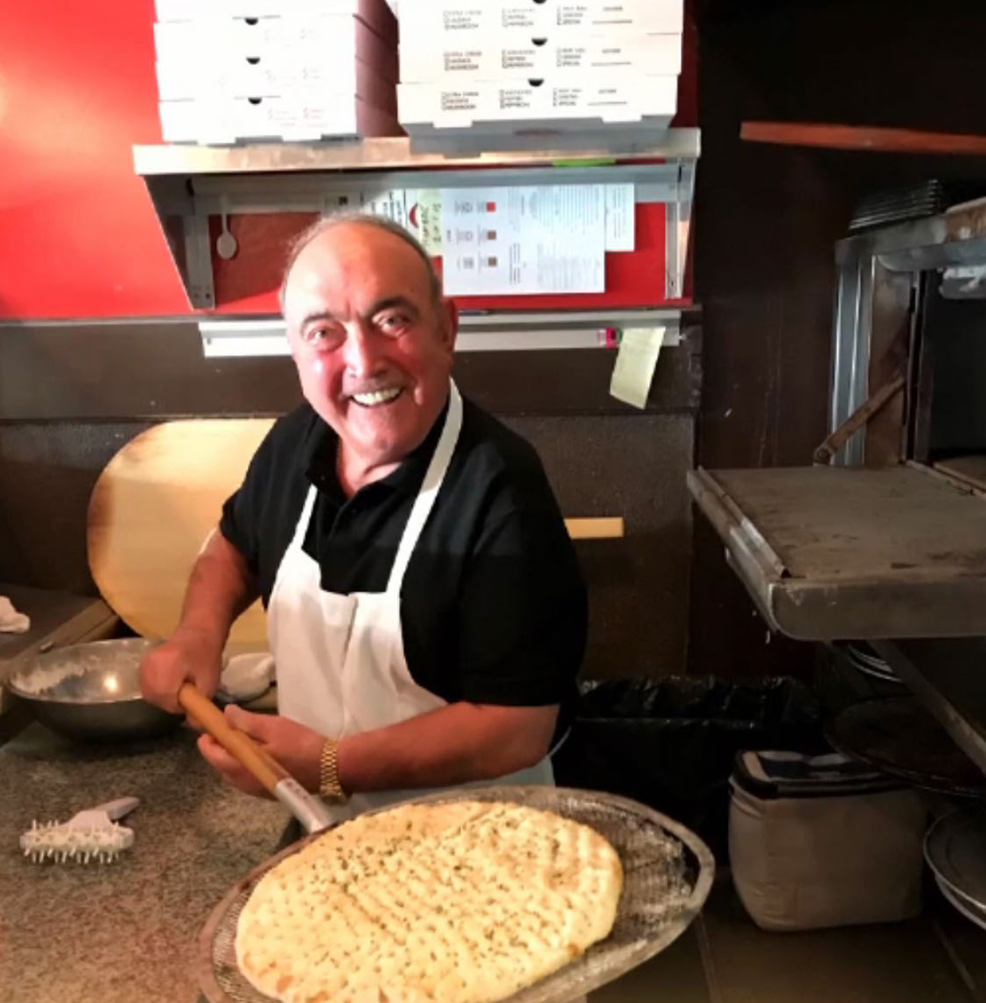 Giacinto Gorga sosteniendo una pizza sobre una piedra.