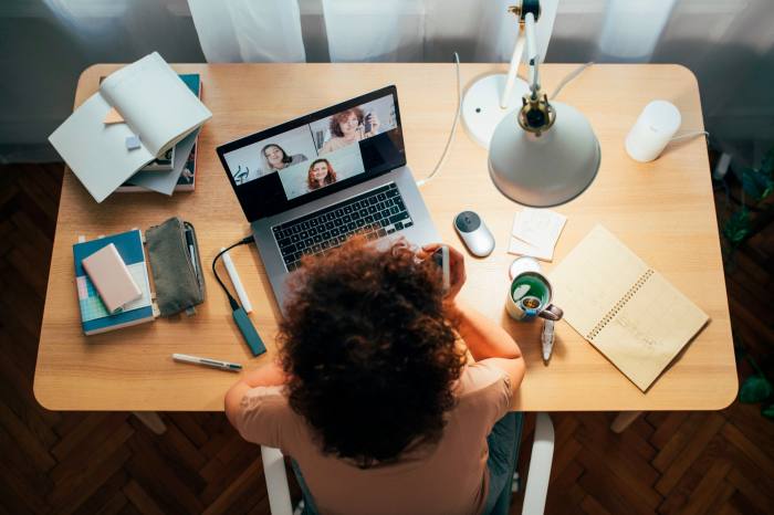 Mujer hablando con personas en una reunión usando su computadora portátil.