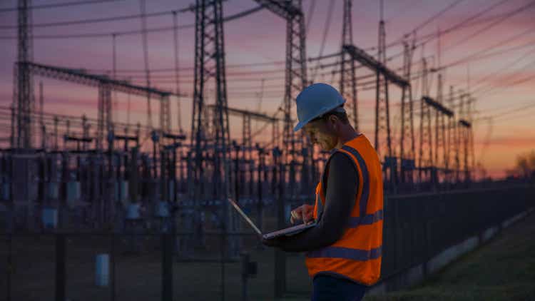 Ingeniero masculino seguro que usa una computadora portátil frente a la central eléctrica