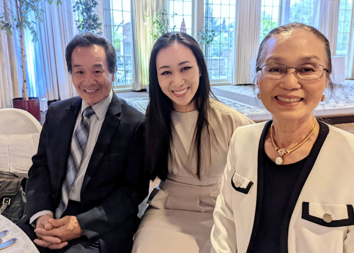 Un padre, una hija y una madre sonríen para una foto.