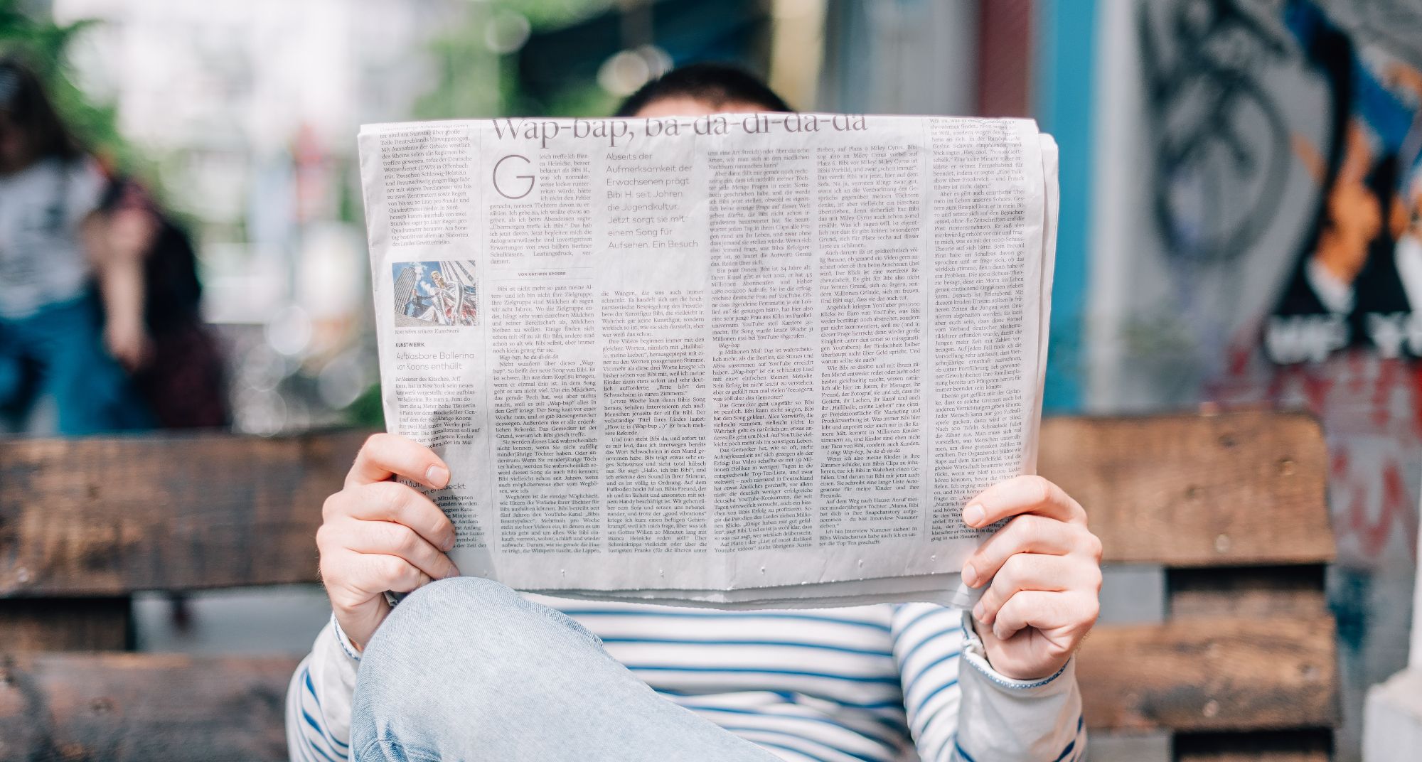 persona leyendo el periódico en un banco