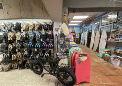 Sandalias y bodyboards Olukai en la parte delantera de Nomad Surf Shop