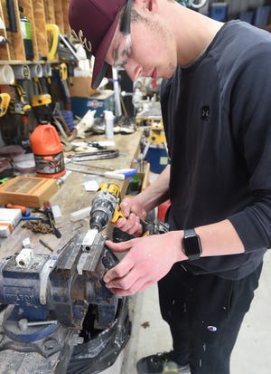 Andrew Aspden, de 17 años, limpia el interior de un bolígrafo personalizado que está haciendo en el taller de su familia en North East Township.