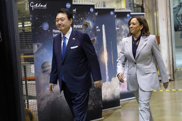 El presidente de Corea del Sur, Yoon Suk Yeol, y la vicepresidenta Kamala Harris pasan por cuatro paneles marcados como Goddard que muestran imágenes de planetas y lanzamientos exitosos de la NASA.