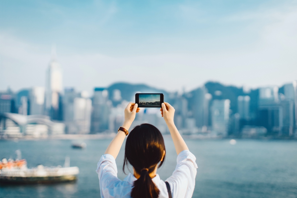 Mujer tomando una foto del horizonte de Hong Kong con un teléfono inteligente