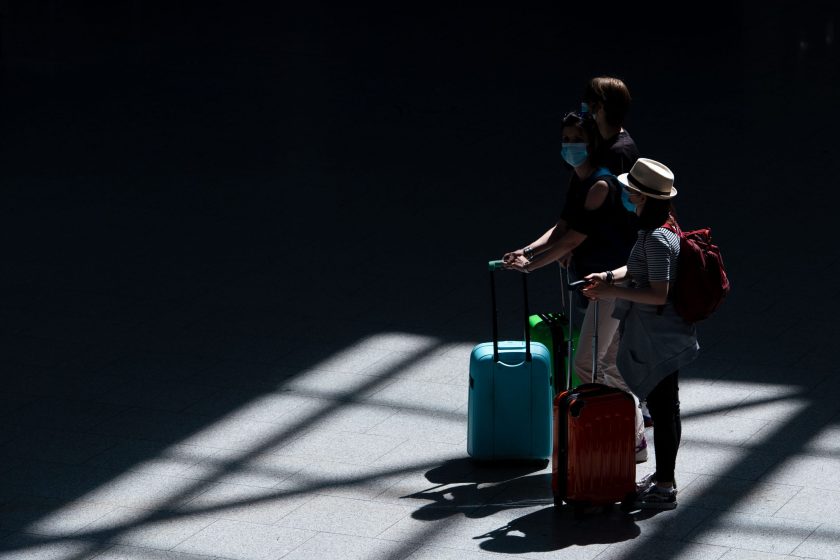 Los viajeros caminan por la sala de salidas del aeropuerto con sus maletas.