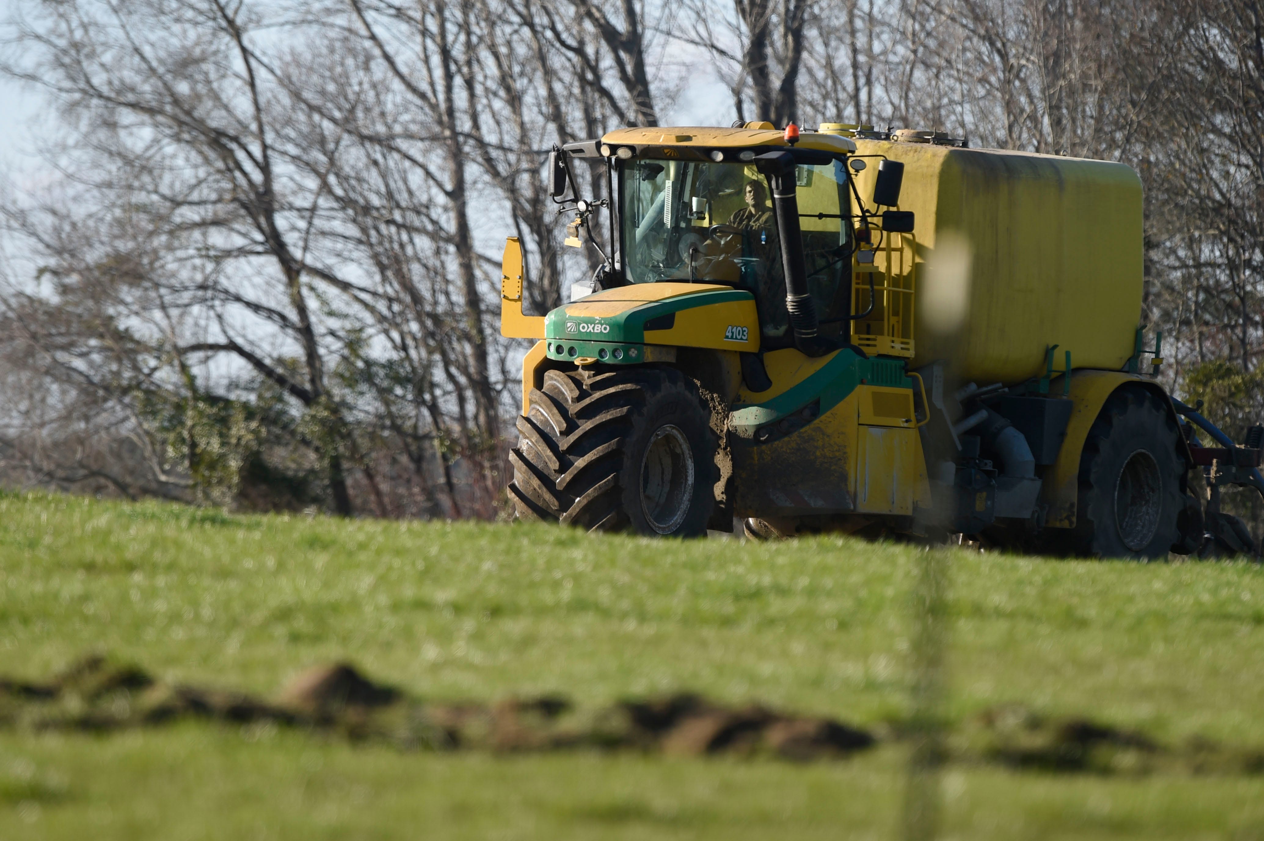 Un tractor tirando de un tanque lleno de enmiendas para el suelo rocía el suelo en una granja cerca del condado de Warren, Georgia, el 26 de enero de 2023.