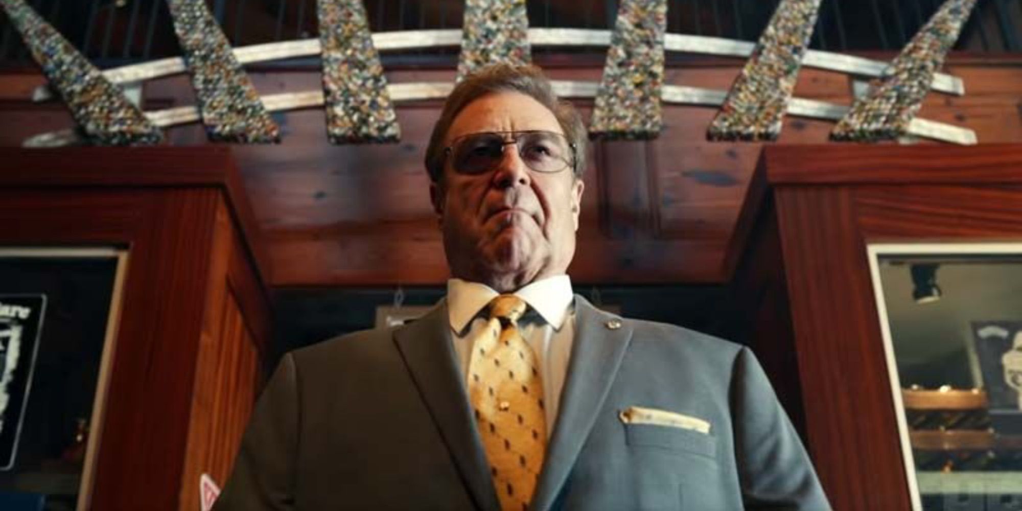 Una vista de ángulo bajo de John Goodman en The Righteous Gemstones, vestido con traje y anteojos.