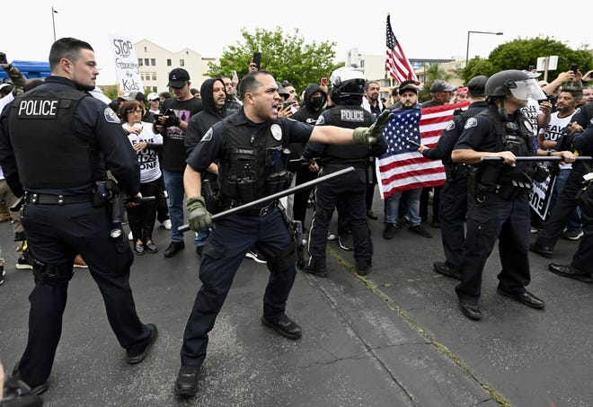 Los grupos conservadores y los defensores de los derechos LGBTQ+ protestan mientras la policía intenta mantener el orden frente a las oficinas del Distrito Escolar Unificado de Glendale en Glendale, California.