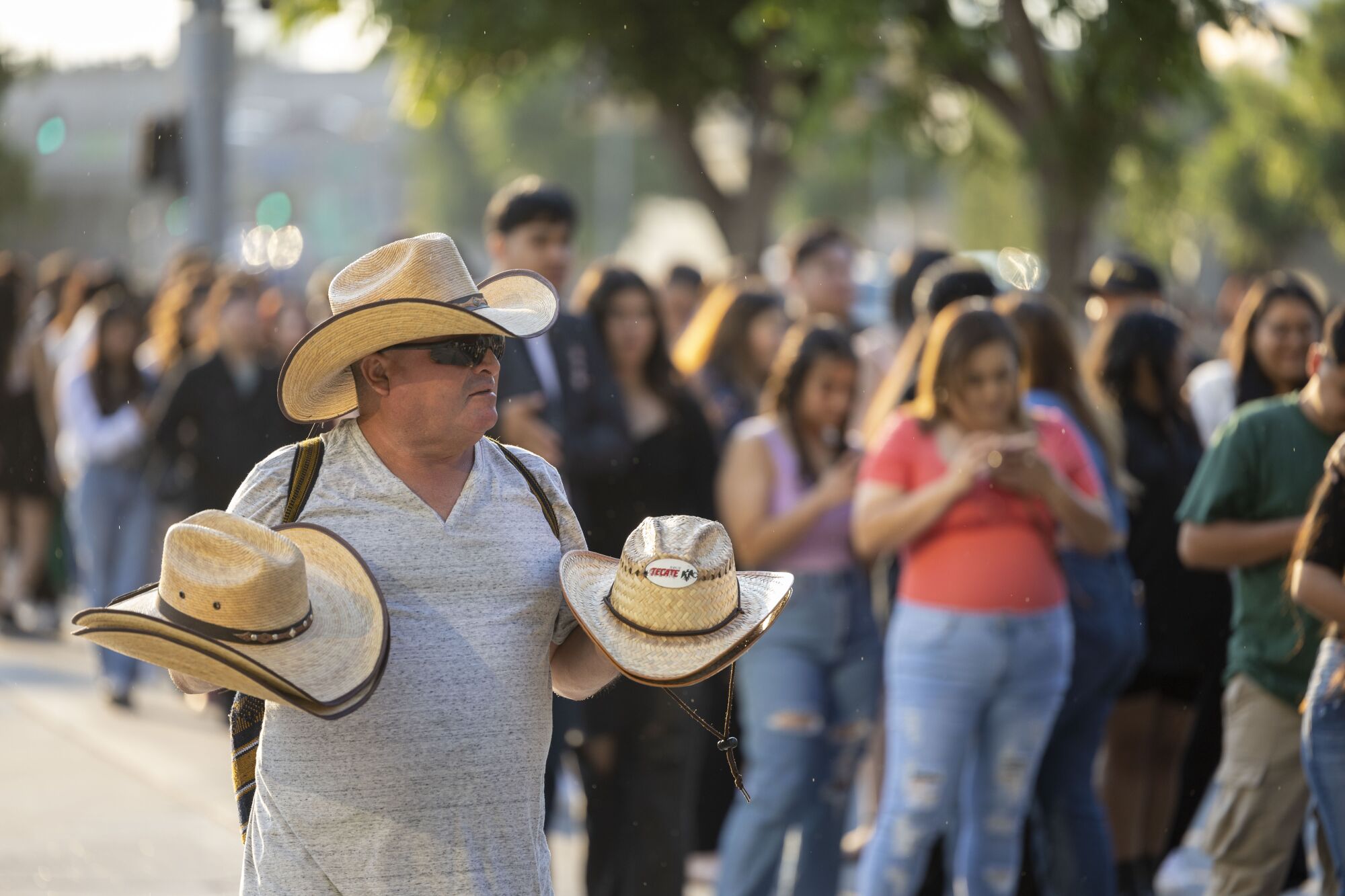 Un vendedor de sombreros camina a lo largo de una fila de personas en fila.