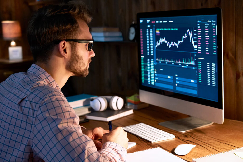 Un hombre mirando un gráfico de criptomonedas en su computadora, que representa intercambios de criptomonedas.