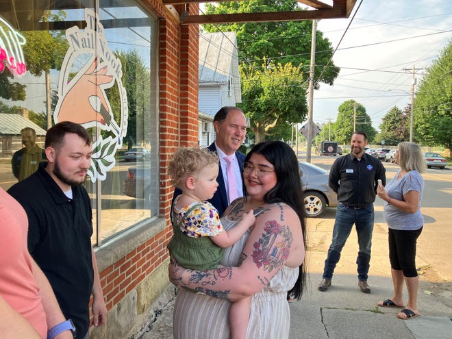 Rebekah Elliott sostiene a su hija de 17 meses, Nora, en el corte de cinta de su nuevo negocio, Nail Nook, el viernes por la mañana.  El alcalde de Shelby, Steve Schag, está al fondo.