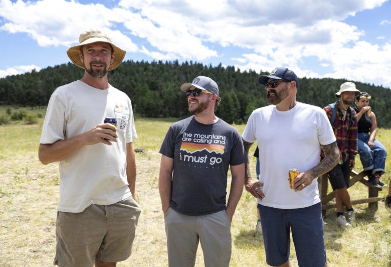 tres hombres de pie con cervezas en la mano