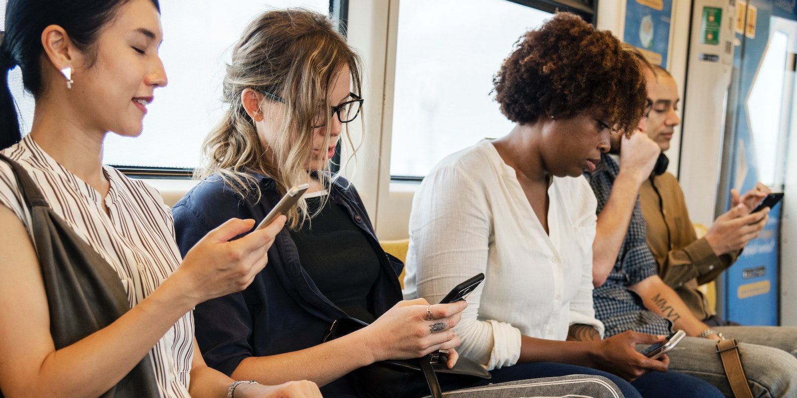 Varios viajeros utilizan sus teléfonos inteligentes mientras viajan en tren