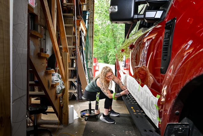 Raychel O'Donoghue, propietaria de Lexington Signs & Graphics, trabaja rotulando una camioneta dentro de su tienda en Burlington, el 21 de agosto de 2023.