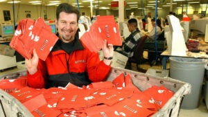 El director ejecutivo de Netflix, Reed Hastings, muestra DVD listos para enviar por correo en un centro de clasificación de San José, California, en 2002. La compañía anunció el martes 18 de abril de 2023 que cerraría su negocio de alquiler de DVD este año.