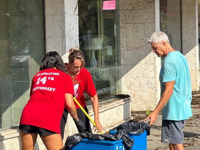 Ele Miccio, propietaria del restaurante Venezia de St. Armands Circle, barre los escombros del huracán Idalia el jueves 31 de agosto de 2023 por la mañana en Sarasota con su esposo y su hija.  Dijo que el agua estancada llegaba aproximadamente a dos pies de la puerta de su negocio.