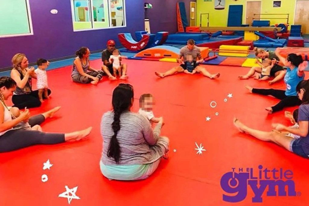 Padres sentados en una colchoneta con niños pequeños en The Little Gym.