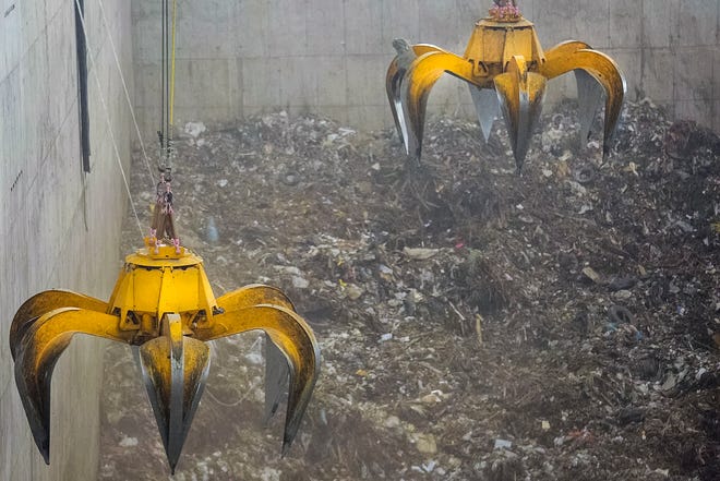 Las garras montadas en grúas agarran montones de basura y restos de plantas del piso del pozo de la instalación de generación de energía del incinerador en el campus de la Autoridad de Residuos Sólidos en West Palm Beach el 19 de mayo de 2015. Las garras mueven los escombros a las bocas de los incineradores.