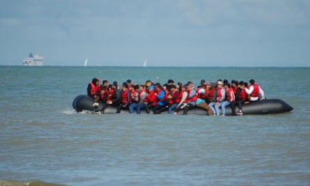 Los inmigrantes se sientan a bordo de un bote inflable antes de intentar cruzar ilegalmente el Canal de la Mancha para llegar a Gran Bretaña.