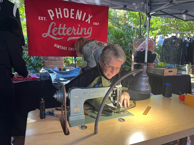 Sue Castelletti opera una máquina de coser cadeneta en el centro del stand de Phoenix Lettering en el Phoenix Flea Market 2023 el 25 de noviembre de 2023.