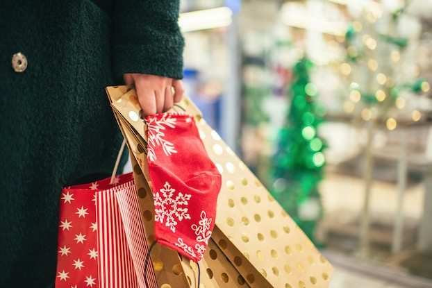     Persona sosteniendo bolsas de regalo mientras hace compras navideñas.