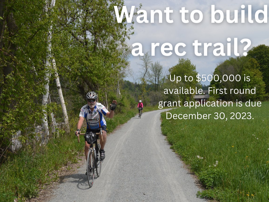 Imagen de una pareja andando en bicicleta por un sendero recreativo.  Lecturas de texto "¿Quieres construir un sendero recreativo?  Hay hasta $500,000 disponibles.  La solicitud de subvención de la primera ronda vence el 30 de diciembre de 2023."