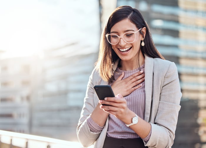 Una persona mira un teléfono inteligente con una expresión de sorpresa en su rostro.