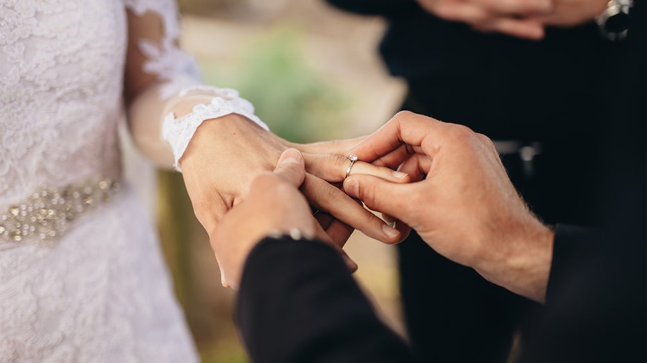 El novio pone el anillo de boda en el dedo de la novia.