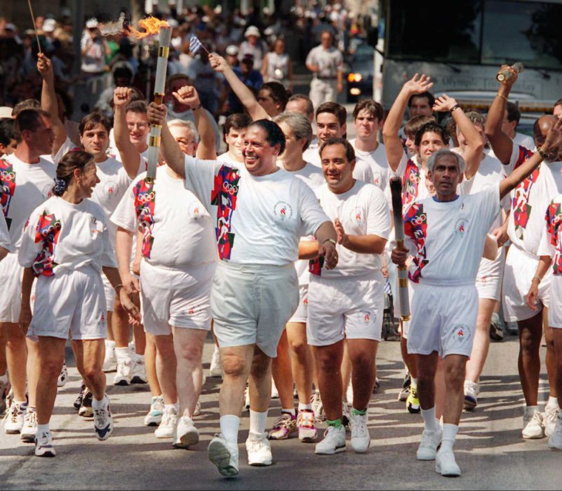 El ex alcalde de Atlanta, Maynard Jackson, lleva la antorcha antes de las ceremonias de apertura de los Juegos Olímpicos de Verano de 1996.  Durante su tercer mandato, Jackson implementó sus agresivas políticas de acción afirmativa en la planificación de la ciudad para los Juegos.  (Greg Lovett/foto del AJC de 1996)