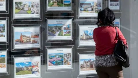 Getty Images Persona mirando por la ventana de un agente inmobiliario