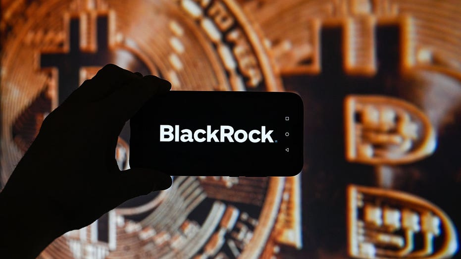 Una ilustración muestra el logotipo de BlackRock en un teléfono inteligente con una criptomoneda de fondo.