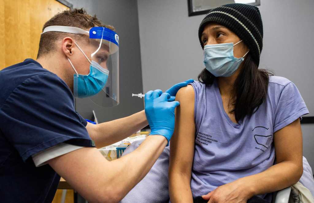 Una mujer es vacunada con la vacuna Pfizer-BioNTech Covid-19 por el doctor Galen Harnden en La Colaborativa en Chelsea, Massachusetts.