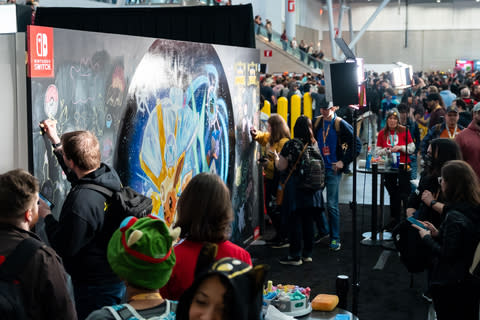 En esta foto proporcionada por Nintendo of America, los fanáticos se reúnen para ver un mural que presenta un Eevee “terastalizante” de los juegos Pokémon Escarlata y Pokémon Violeta en PAX East.