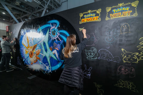 En esta foto proporcionada por Nintendo of America, Shaylin D. añade un mural temático de Pokémon Escarlata y Pokémon Violeta en PAX East.