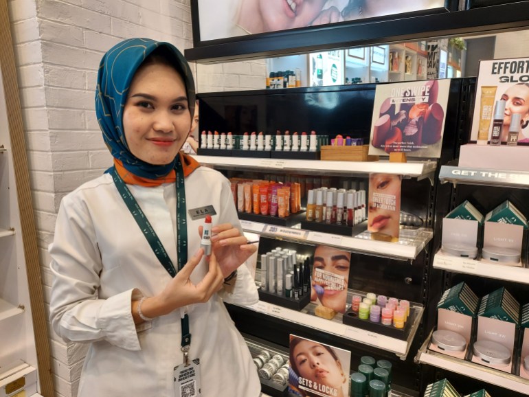 Ela, vendedora de Body Shop, está planeando un maquillaje extravagante para las fiestas que incluye un lápiz labial de colores brillantes. [Aisyah Llewellyn/Al Jazeera]