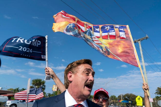 Mike Lindell, director ejecutivo de My Pillow Inc, saluda a los partidarios de Trump mientras esperan a lo largo de la ruta de la caravana a que el expresidente Donald Trump regrese a su casa en Mar-a Lago luego de su lectura de cargos en Nueva York el 4 de abril de 2023.