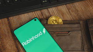 stock de capucha: Una imagen de una billetera con una moneda dentro, un teléfono celular en la parte superior que representa el logotipo de Robinhood.  Cripto Robinhood