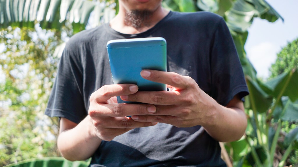 Foto de un hombre en Indonesia sosteniendo un teléfono inteligente, utilizada en una publicación sobre la aplicación de inversión Pluang