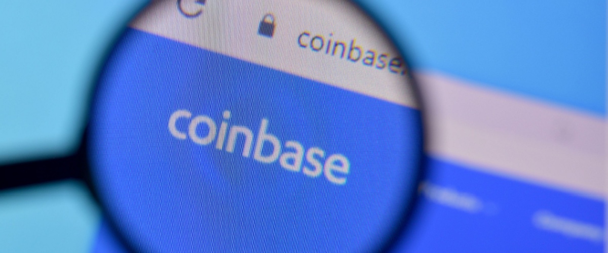 El sitio web de Coinbase en una computadora de escritorio, ampliado con una lupa