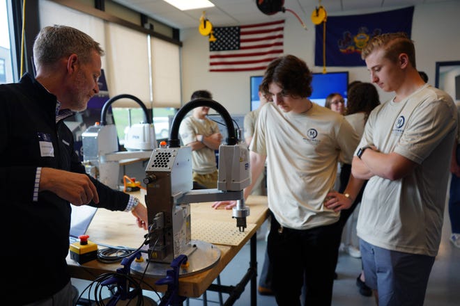 Grant Schiefferle, izquierda, de Factory Automation Components, muestra un brazo robótico a los estudiantes de McDowell James Kutz, centro, y Jacob Baniewicz.