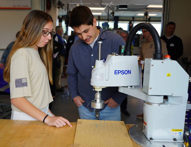 Kendall Klapsinos, estudiante de McDowell, y Caleb Sanford, propietario de Epworth Automation, observan un brazo robótico en funcionamiento.