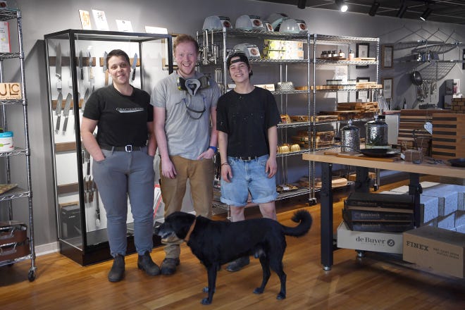 Sarah Fiori, izquierda, Sam Garner y Lucie Tremblay con el perro de tienda Pate en The Crafted Edge en Eagle Street en Asheville, el 1 de mayo de 2024.