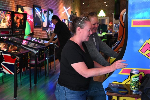 Shannon Ronan, izquierda, y su esposa Breelyn MacDonald de San Rafael juegan un juego antiguo en Pixels Arcade Taproom en San Rafael, California, el viernes 1 de junio de 2024. (Sherry LaVars/Marin Independent Journal)