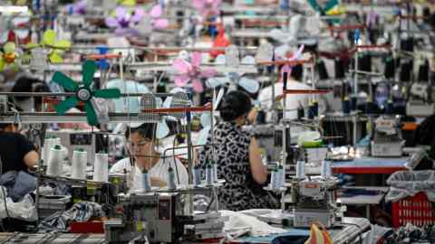 Trabajadores en filas de mesas utilizando máquinas de coser.