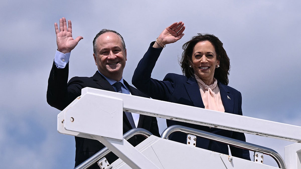 Kamala Harris con su esposo Doug Emhoff, saludando desde los escalones del Air Force Two